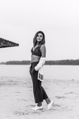 Seyahat konsepti. Sahilde genç bir kadının felsefi fotoğrafı. Kıyafetlerde minimalizm  