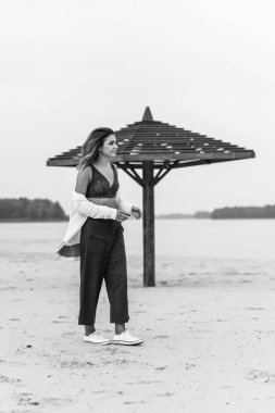 Seyahat konsepti. Sahilde genç bir kadının felsefi fotoğrafı. Kıyafetlerde minimalizm  