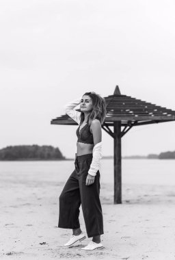 Seyahat konsepti. Sahilde genç bir kadının felsefi fotoğrafı. Kıyafetlerde minimalizm  