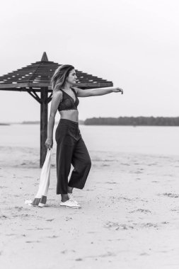 Seyahat konsepti. Sahilde genç bir kadının felsefi fotoğrafı. Kıyafetlerde minimalizm  