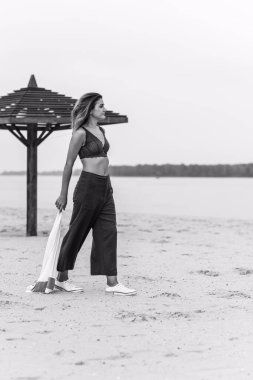 Seyahat konsepti. Sahilde genç bir kadının felsefi fotoğrafı. Kıyafetlerde minimalizm  