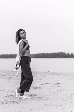 Seyahat konsepti. Sahilde genç bir kadının felsefi fotoğrafı. Kıyafetlerde minimalizm  