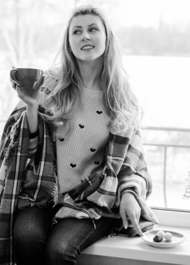 Kendini izole etmiş, sıcak kahve içen, rahat bir evde, ekoseli bir evde oturan sevimli bir kadın. Mutluluk konsepti ve neşeli yaşam tarzı, oldukça rahat bir sabah.