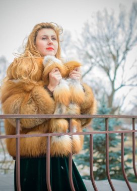 Kaliteli giyinmiş şık bir bayan. O, kadife bir elbise ve açık kırmızı bir kürk ceket giydi. Modern hayatta 50 'li yaşlar