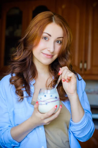 European or American woman at morning eat homemade organic yogurt with fresh berries. Homemade yogurt in girl`s hands. Health care and diet and breakfast cereal. Healthy eating and lifestyle concept