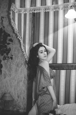 Yatak odasında gül ve romantik ruh hali olan hoş bir kadının fotoğrafı, bugünü kutlayın, kıvırcık saç stili, çekici vücut yatak kadınsı konseptinde poz veriyor.