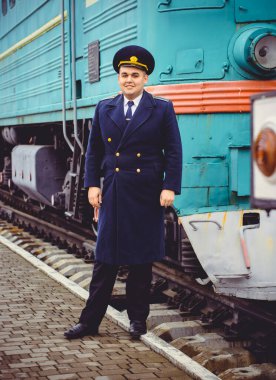 Avrupalı ya da Amerikalı tren kondüktörü bir platformda ve diğer trenlerde görevdedir. Demiryolu, buharlı trenler, klasik trenler.