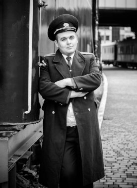 Avrupalı ya da Amerikalı tren kondüktörü bir platformda ve diğer trenlerde görevdedir. Demiryolu, buharlı trenler, klasik trenler.