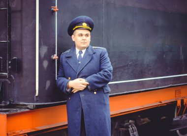 Avrupalı ya da Amerikalı tren kondüktörü bir platformda ve diğer trenlerde görevdedir. Demiryolu, buharlı trenler, klasik trenler.