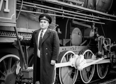 Avrupalı ya da Amerikalı tren kondüktörü bir platformda ve diğer trenlerde görevdedir. Demiryolu, buharlı trenler, klasik trenler.
