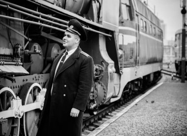 Avrupalı ya da Amerikalı tren kondüktörü bir platformda ve diğer trenlerde görevdedir. Demiryolu, buharlı trenler, klasik trenler.