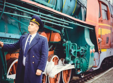 Avrupalı ya da Amerikalı tren kondüktörü bir platformda ve diğer trenlerde görevdedir. Demiryolu, buharlı trenler, klasik trenler.