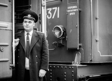 Avrupalı ya da Amerikalı tren kondüktörü bir platformda ve diğer trenlerde görevdedir. Demiryolu, buharlı trenler, klasik trenler.