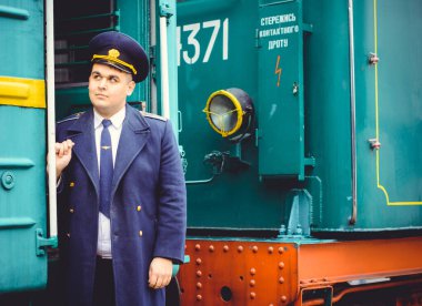 Avrupalı ya da Amerikalı tren kondüktörü bir platformda ve diğer trenlerde görevdedir. Demiryolu, buharlı trenler, klasik trenler.