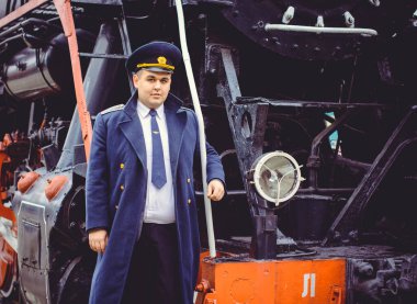 Avrupalı ya da Amerikalı tren kondüktörü bir platformda ve diğer trenlerde görevdedir. Demiryolu, buharlı trenler, klasik trenler.