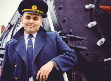 Avrupalı ya da Amerikalı tren kondüktörü bir platformda ve diğer trenlerde görevdedir. Demiryolu, buharlı trenler, klasik trenler.