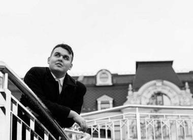 Genç ve cüsseli adam rahatlıyor ve manzaranın tadını çıkarıyor. Büyük şehir yaşamındaki tombul insanlar konsepti. Şehir merkezindeki şişman iş adamının görüntüsü