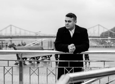 Genç ve cüsseli adam rahatlıyor ve manzaranın tadını çıkarıyor. Büyük şehir yaşamındaki tombul insanlar konsepti. Şehir merkezindeki şişman iş adamının görüntüsü