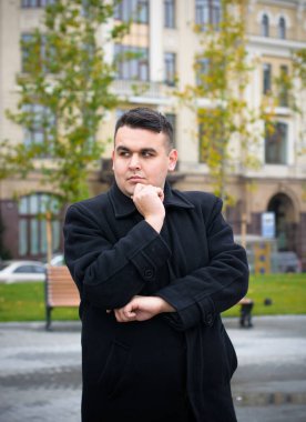 Genç ve cüsseli adam rahatlıyor ve manzaranın tadını çıkarıyor. Büyük şehir yaşamındaki tombul insanlar konsepti. Şehir merkezindeki şişman iş adamının görüntüsü