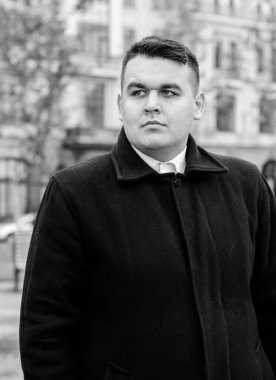 Genç ve cüsseli adam rahatlıyor ve manzaranın tadını çıkarıyor. Büyük şehir yaşamındaki tombul insanlar konsepti. Şehir merkezindeki şişman iş adamının görüntüsü