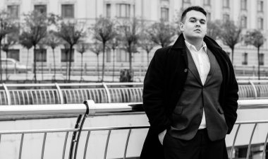 Genç ve cüsseli adam rahatlıyor ve manzaranın tadını çıkarıyor. Büyük şehir yaşamındaki tombul insanlar konsepti. Şehir merkezindeki şişman iş adamının görüntüsü