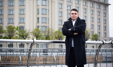 Genç ve cüsseli adam rahatlıyor ve manzaranın tadını çıkarıyor. Büyük şehir yaşamındaki tombul insanlar konsepti. Şehir merkezindeki şişman iş adamının görüntüsü