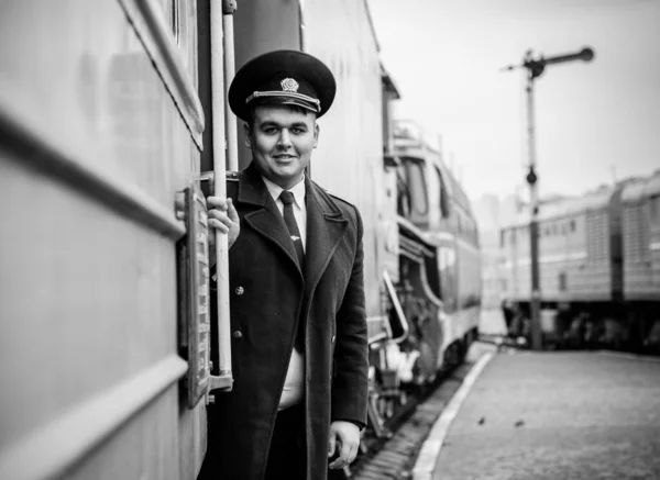 Avrupalı ya da Amerikalı tren kondüktörü bir platformda ve diğer trenlerde görevdedir. Demiryolu, buharlı trenler, klasik trenler.