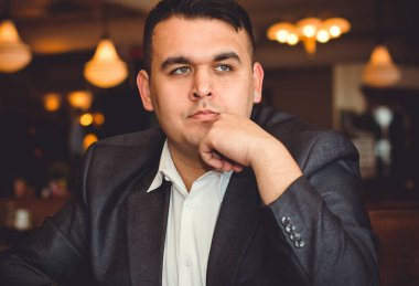 Genç ve cüsseli adamlar restoranda rahatlıyor ve eğleniyorlar, tombul insanlar konsepti, büyük şehir hayatı. Kilolu iş adamının bir şeyler düşündüğü görüntüsü.