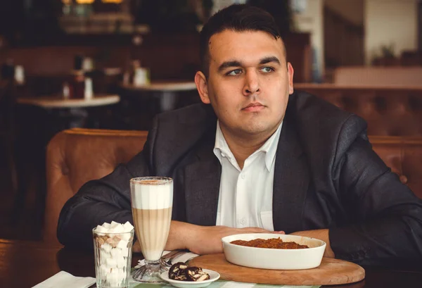 Young plus size with eating croissant and drink coffee , alone concept or lonely in big city life. Image of overweight businessman at downtown sit at restaurant
