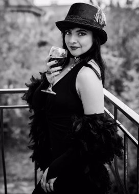 Vintage şıklığı. Klasik tonlarda portre ve siyah aksesuarlı kadın balkonda durup eğleniyor. Eski moda konsepti