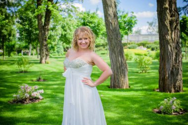 Parkta romantik şefkat gelini. Genç bayan yaz bahçesinde eğleniyor. Düğün gününde poz veren güzel bir gelin, gelinlikli güzel bir kız. 