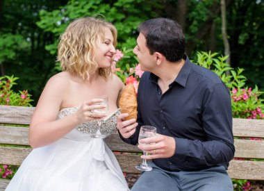 Düğünde sarışın gelin ve damat. Mutlu evlilik çifti. Güzel gelin, beyaz elbiseli genç bayan damadı öpüyor ve yaz günü dışarıda eğleniyor. Yeni evlenmiş, genç bir aile..