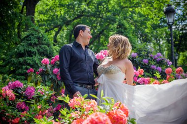 Düğünde sarışın gelin ve damat. Mutlu evlilik çifti. Güzel gelin, beyaz elbiseli genç bayan damadı öpüyor ve yaz günü dışarıda eğleniyor. Yeni evlenmiş, genç bir aile..