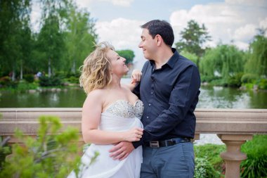 Düğünde sarışın gelin ve damat. Mutlu evlilik çifti. Güzel gelin, beyaz elbiseli genç bayan damadı öpüyor ve yaz günü dışarıda eğleniyor. Yeni evlenmiş, genç bir aile..