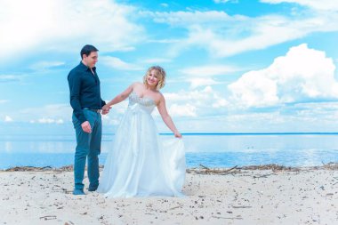 Düğünde sarışın gelin ve damat. Mutlu evlilik çifti. Güzel gelin, beyaz elbiseli genç bayan damadı öpüyor ve yaz günü dışarıda eğleniyor. Yeni evlenmiş, genç bir aile..