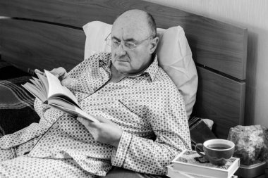 Evde yatakta yatan son sınıf öğrencisi için endişelendim. Yatakta yatan olgun bir adam pijama giyer, acı hisseder, hastalanır..