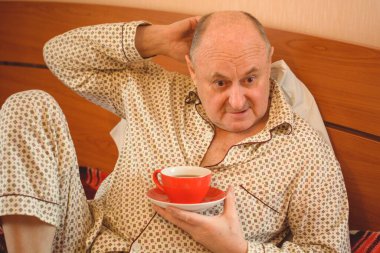 Evde yatakta yatan son sınıf öğrencisi için endişelendim. Yatakta yatan olgun bir adam pijama giyer, acı hisseder, hastalanır..