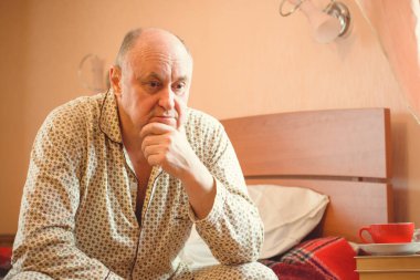 Evde yatakta yatan son sınıf öğrencisi için endişelendim. Yatakta yatan olgun bir adam pijama giyer, acı hisseder, hastalanır..