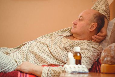 Evde yatakta yatan son sınıf öğrencisi için endişelendim. Yatakta yatan olgun bir adam pijama giyer, acı hisseder, hastalanır..