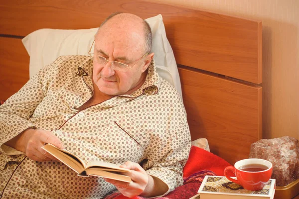 Worried senior lying in bed at home. Mature man lying in bed wear in pajamas, feeling pain, sick.