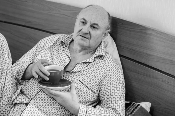 Evde yatakta yatan son sınıf öğrencisi için endişelendim. Yatakta yatan olgun bir adam pijama giyer, acı hisseder, hastalanır..