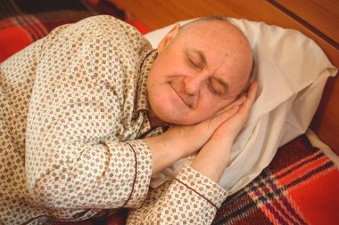 Yaşlı adam rahat bir yerde, yatak odasında oyuncakla pijamalarıyla uyur, emekli olur.