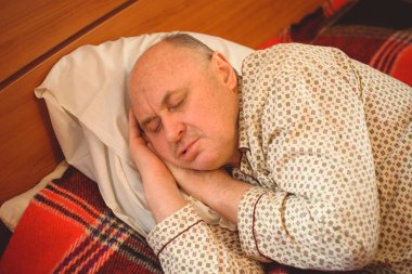 Yaşlı adam rahat bir yerde, yatak odasında oyuncakla pijamalarıyla uyur, emekli olur.