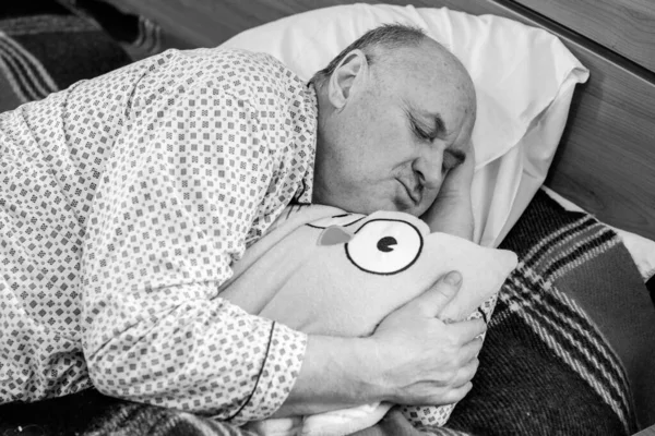 Yaşlı adam rahat bir yerde, yatak odasında oyuncakla pijamalarıyla uyur, emekli olur.