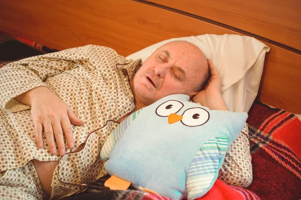 Yaşlı adam rahat bir yerde, yatak odasında oyuncakla pijamalarıyla uyur, emekli olur.