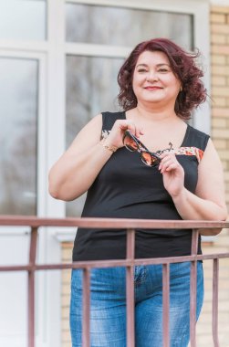 Orta yaşlı ve hayattan zevk alan iri yarı bir kadın. Aşırı kilolu, şık giyinmiş olgun bir bayan. Doğal güzellik.