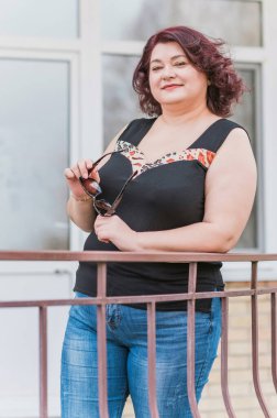 Orta yaşlı ve hayattan zevk alan iri yarı bir kadın. Aşırı kilolu, şık giyinmiş olgun bir bayan. Doğal güzellik.