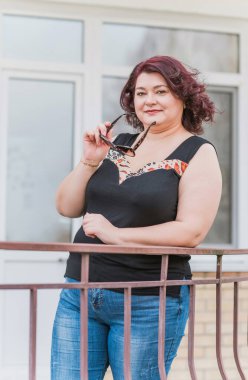 Orta yaşlı ve hayattan zevk alan iri yarı bir kadın. Aşırı kilolu, şık giyinmiş olgun bir bayan. Doğal güzellik.