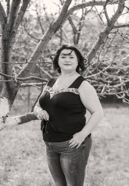 Orta yaşlı ve hayattan zevk alan iri yarı bir kadın. Aşırı kilolu, şık giyinmiş olgun bir bayan. Doğal güzellik.