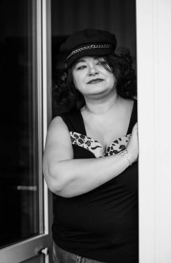 Orta yaşlı ve hayattan zevk alan iri yarı bir kadın. Aşırı kilolu, şık giyinmiş olgun bir bayan. Doğal güzellik.